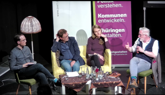 Podiumsdiskussion Klimaschutz und Denkmalschutz vom 04.05.23 im 3K in Mühlhausen Podiumsdiskussion. Vier Menschen sitzen um einen Tisch auf Stühlen und einem Sofa in der Mitte. Von links nach rechts sind es: Der Moderator, Steffen Thormann, Dr. Johannes Bruns (Oberbürgermeister von Mühlhausen), Laura Wahl (Mitglied des Landtages für Bündnis'90/Die Grünen) und Proffessor Dr. Benjamin-Imanuel Hoff (Kulturminister Thüringens),