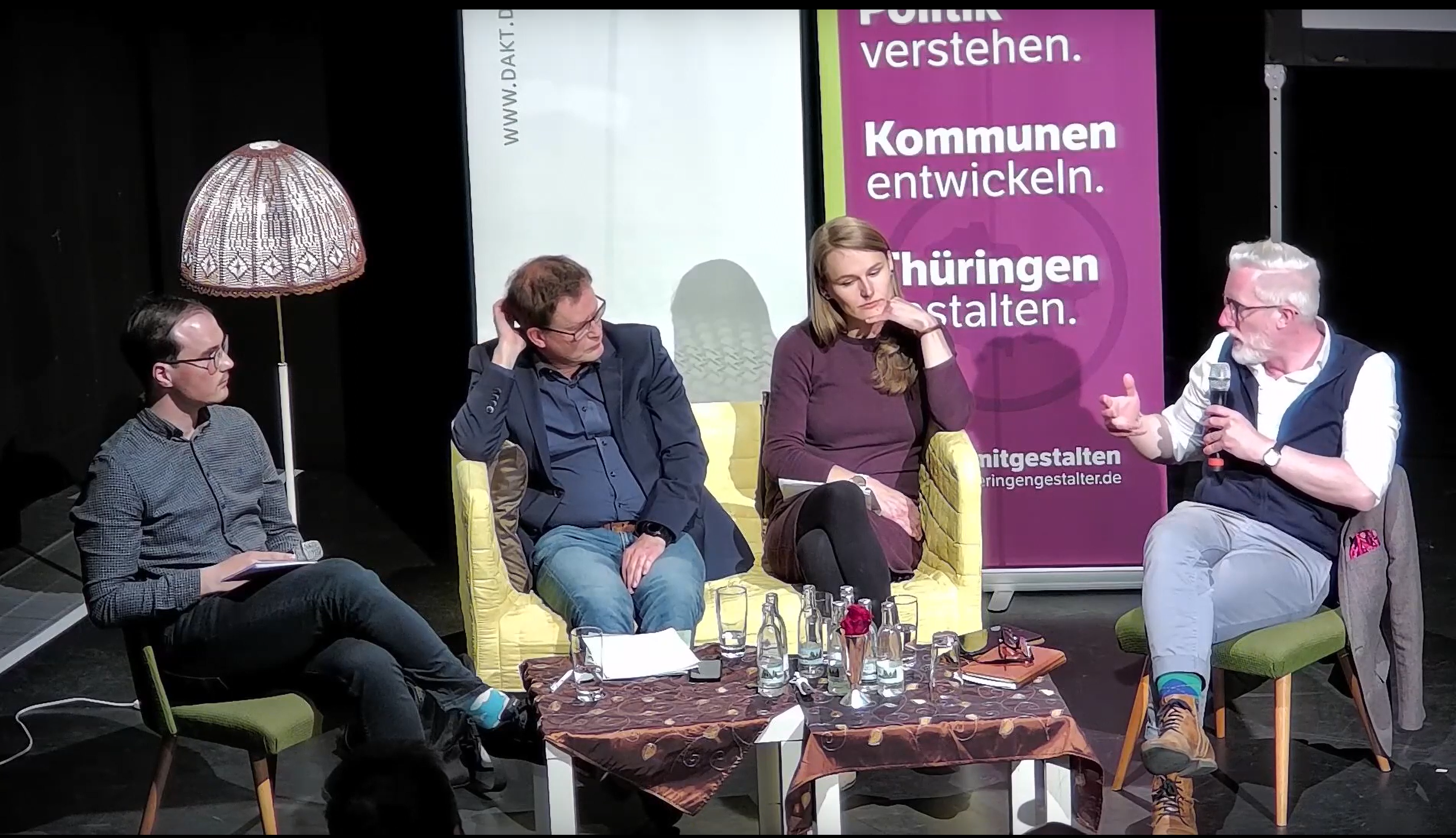 Podiumsdiskussion Klimaschutz und Denkmalschutz vom 04.05.23 im 3K in Mühlhausen Podiumsdiskussion. Vier Menschen sitzen um einen Tisch auf Stühlen und einem Sofa in der Mitte. Von links nach rechts sind es: Der Moderator, Steffen Thormann, Dr. Johannes Bruns (Oberbürgermeister von Mühlhausen), Laura Wahl (Mitglied des Landtages für Bündnis'90/Die Grünen) und Proffessor Dr. Benjamin-Imanuel Hoff (Kulturminister Thüringens),