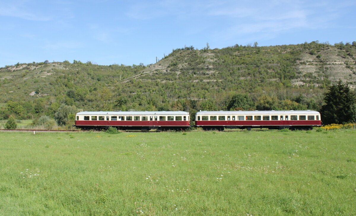 Eine alte Diesellock Fährt durch eine grüne Landschaft. Sie ist Seitlich zu sehen und ist mittig im Bild platziert.